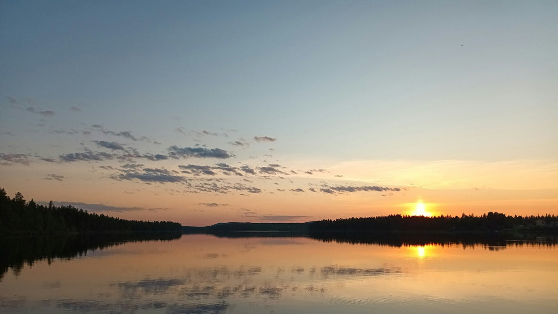 Sommerabend in Finnland – Sonnenuntergang über einem stillen See mit Waldsilhouette, orangefarbenes Licht spiegelt sich im Wasser
