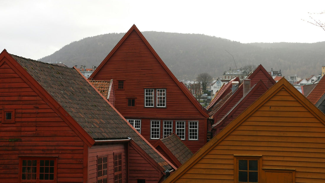 Traditionelle Holzhäuser in Rot- und Ockertönen in Stavangar, Norwegen, mit Bergen im Hintergrund