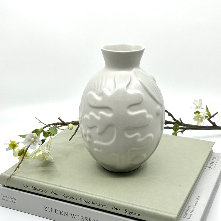 Anna-Lisa Thomson Keramikvase auf Büchern: Handgefertigte Vase mit Reliefmuster, inszeniert mit weißen Blütenzweigen auf Büchern – seltene schwedische Keramikkunst der 1940er und dekorative Eleganz