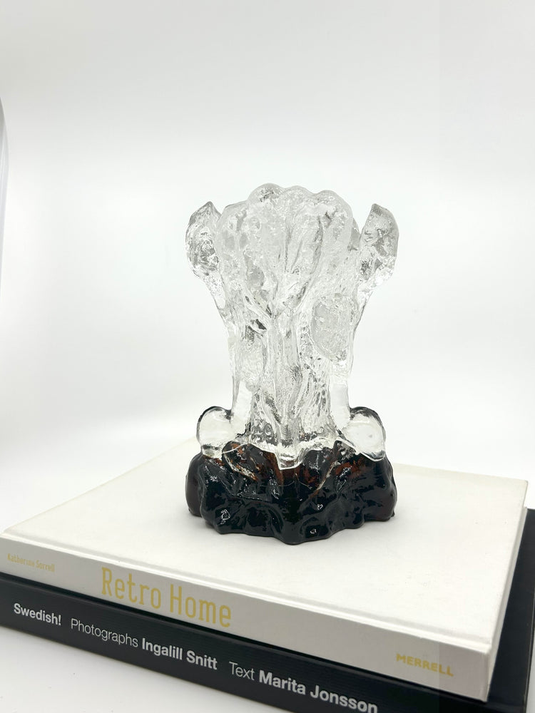 Klare Pertti Santalahti Vase von Humppila aus den 70er Jahren, organische Form mit braun-schwarzem Glasfuß, stehend auf zwei Designbüchern.