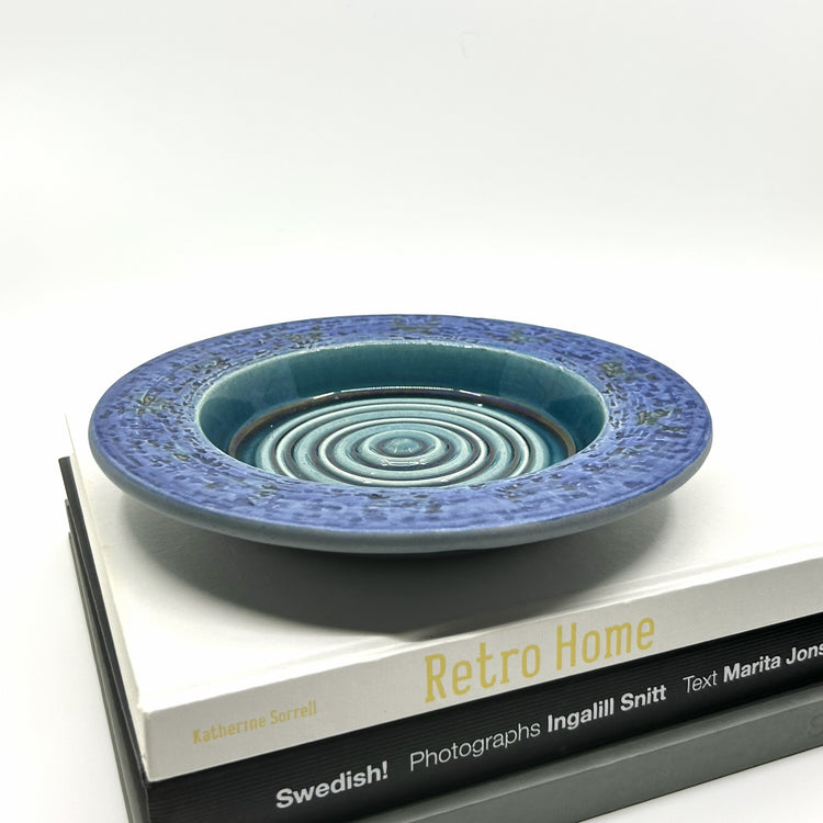 Göran Andersson 'Anakonda' Keramikschale auf Buch 'Swedish! Retro Home': Dekorative Schale mit blauer Glasur und markantem Design – skandinavisches Interieur und Lifestyle