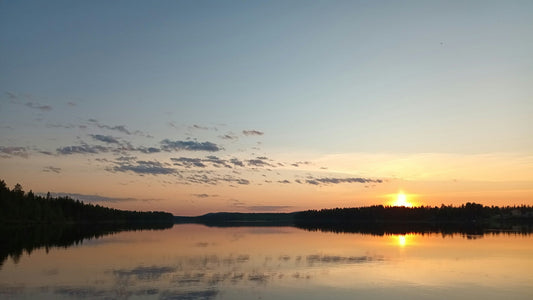 Sommerabend in Finnland – Sonnenuntergang über einem stillen See mit Waldsilhouette, orangefarbenes Licht spiegelt sich im Wasser