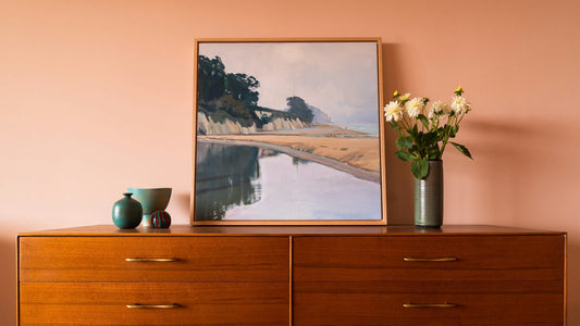 Mid-Century-Modern Interieur mit skandinavischer Kommode aus Teakholz, darauf Keramikvasen, Blumen und ein Landschaftsgemälde an der Wand