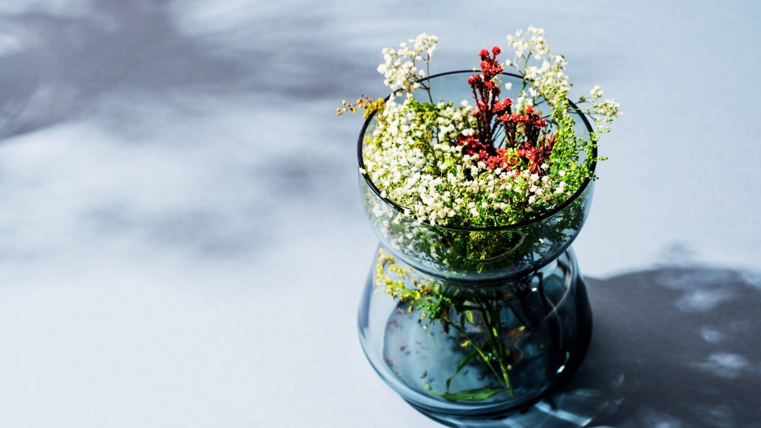 Blaue Glasschale auf zartblauem Grund mit zatren Blüten in weiß und rot gefüllt