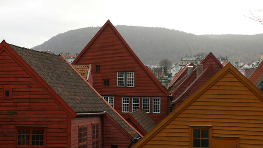 Traditionelle Holzhäuser in Rot- und Ockertönen in Stavangar, Norwegen, mit Bergen im Hintergrund
