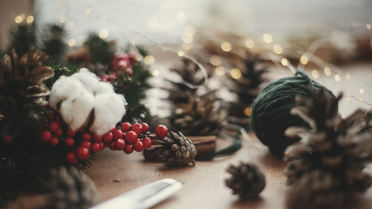 Weinachtsdeko in Rot, weiß und Grün mit Tannenzapgen auf einem Holztisch