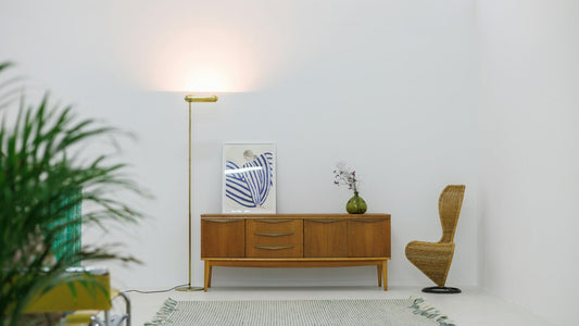 Minimalistisches Interieur mit skandinavischem Sideboard aus Holz, dekoriert mit Vase, Grafik und Lampe, daneben ein Stuhl aus Naturmaterial