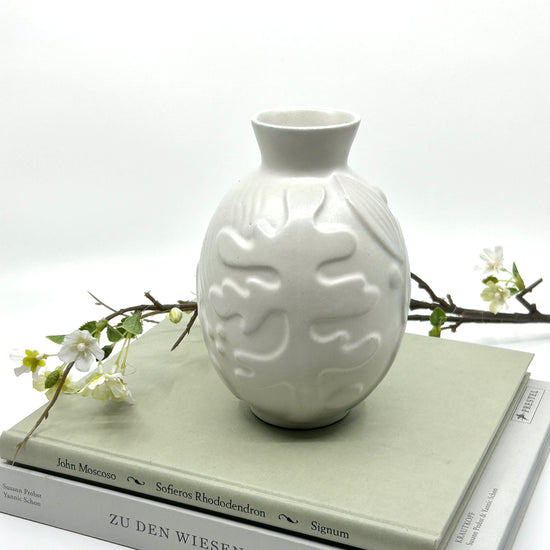Anna-Lisa Thomson Keramikvase auf Büchern: Handgefertigte Vase mit Reliefmuster, inszeniert mit weißen Blütenzweigen auf Büchern – seltene schwedische Keramikkunst der 1940er und dekorative Eleganz
