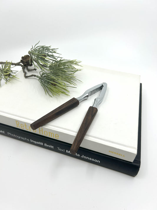 Vintage Teak Nussknacker aus Dänemark, 1950er Jahre, mit Metallzange und dunkelbraunen Holzgriffen im Mid Century Modern Design, stilvoll auf Büchern dekoriert.