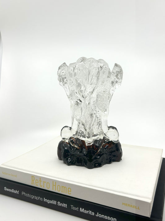 Klare Pertti Santalahti Vase von Humppila aus den 70er Jahren, organische Form mit braun-schwarzem Glasfuß, stehend auf zwei Designbüchern.
