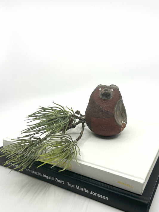 Thomas Hellström Keramikfigur „Bär“ aus den 1980er-Jahren, gefertigt bei Nittsjö, Schweden – rustikale Mid-Century-Dekofigur in Braun auf Bücherstapel mit Tannenzweig inszeniert.