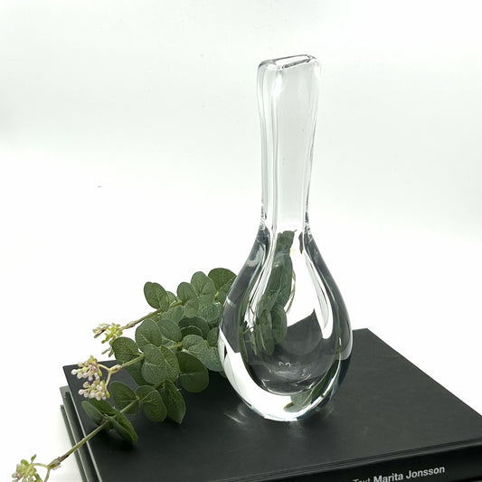 Göran Wörff 'Raindrop' Vase von Kosta Boda, Schweden: Elegante, tropfenförmige Glasvase mit klarer, glatter Oberfläche und zarten Eukalyptuszweigen – skandinavisches Design und handwerkliche Glasbläserkunst