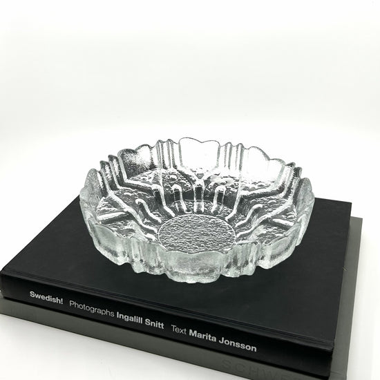 Tauno Wirkkala 'Ulpucca' Dekoschale aus Humppila, Finnland: Handgefertigte Glasschale mit organischen, Strukturen auf schwarzem Buch – finnische Glaskunst und skandinavisches Design